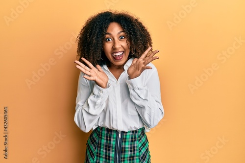 Beautiful african american woman with afro hair wearing scholar skirt celebrating crazy and amazed for success with arms raised and open eyes screaming excited. winner concept