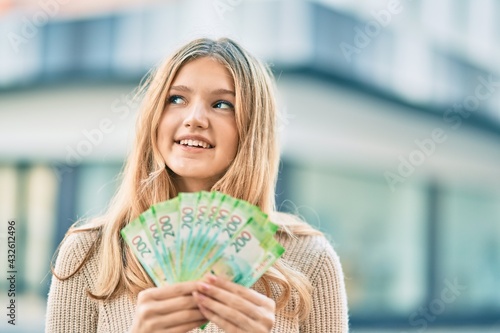 Beautiful caucasian teenager smiling happy holding russian 200 ruble banknotes at the city.