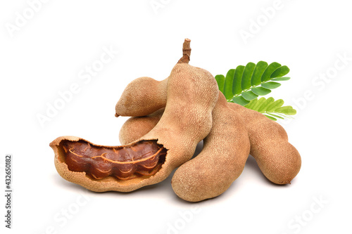 Pile of tamarind fruits with green leaves isolated on white background.