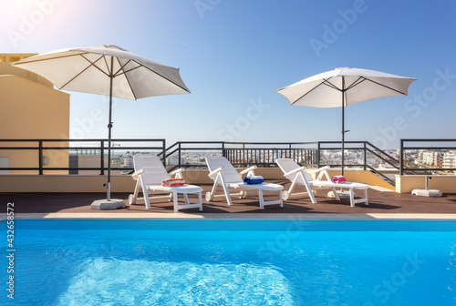 Loungers placed on the right and in the front of a pool with clean looking water on a sunny day.