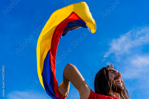 Colombian Latino man with his hand in fist at a protest in Colombia holding a Colombian flag with a blue sky background, copy space