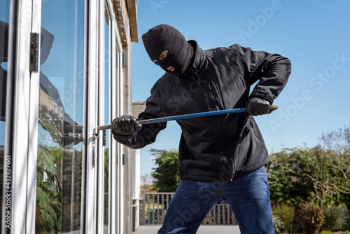 Burglar breaking into a house via a window with a crowbar