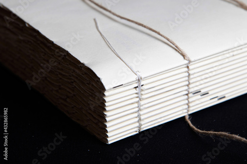 The process of book binding; close up of a raw book after sewing on cords. Black background