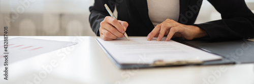 Businesswoman signing a document or application form in a folder