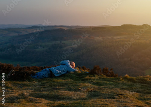 man in grey coat watching sunset and taking video in Peak District 