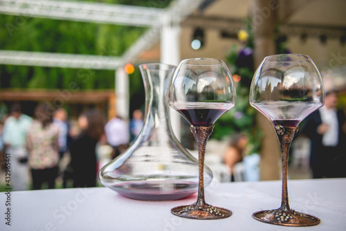 Arrangement with 2 coups of red wine and glass jar in a outdoor wedding in the day