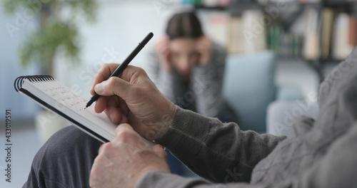 Professional therapist listening to the patient and writing notes