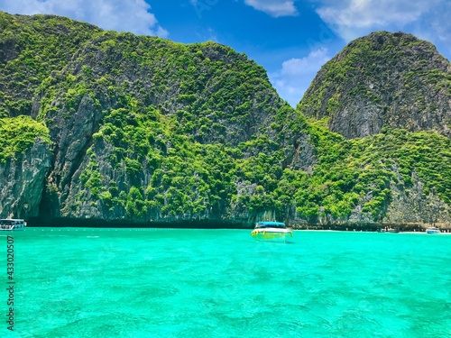 Grüne Vulkaninsel in Thailand mit türkis klarem Wasser umgeben und Booten