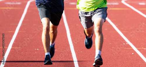 Front view of two runners side by side on a track in sunshine