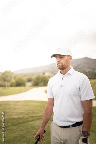Concentrated golf player looking to the hole before swinging. 
