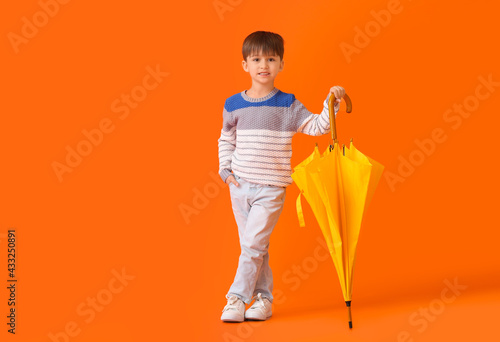 Cute little boy with umbrella on color background