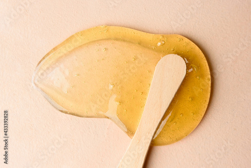Liquid sugar wax smear with spatula on beige background