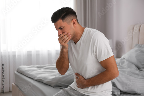 Man suffering from nausea on bed at home. Food poisoning