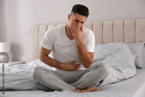 Man suffering from nausea on bed at home. Food poisoning