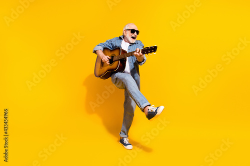 Full length photo of cool happy positive old man dance hold guitar wear sunglass isolated on yellow color background