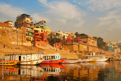 India, Varanasi Ganges river ghat with ancient city architecture as viewed from a boat on the river at sunset.