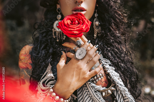 beautiful young gypsy style woman with red rose outdoors