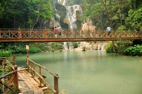 Laotian people foreign travelers travel visit on wooden bridge for looking and take photo at viewpoint of Tat Kuang Si Falls Waterfalls at Luangprabang Lao city on April 8, 2016 in Luang Prabang, Laos