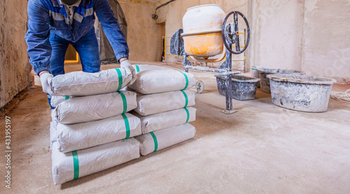 Worker is unloading the bags of cement an apartment is under construction, remodeling, renovation, extension, restoration and reconstruction.