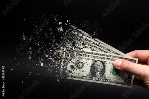 Inflation, dollar hyperinflation with black background. One dollar bill is sprayed in the hand of a man on a black background. The concept of decreasing purchasing power, inflation.