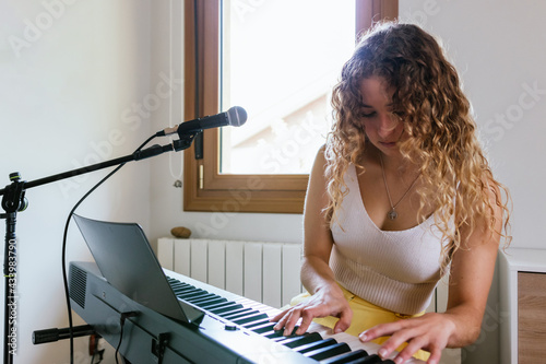 Young woman playing piano at home studio