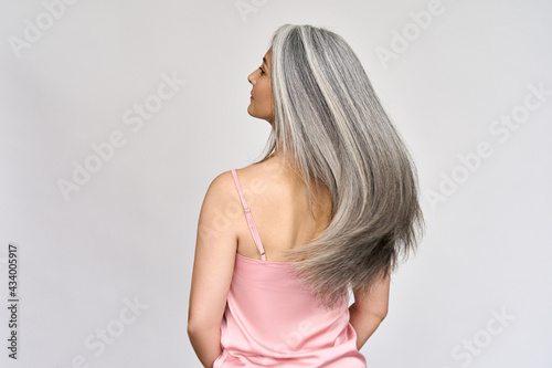 Back view of senior mature middle aged older Asian lady with long gray natural coloring vibrant silky hair. Dry hair replenishing healing treatment for women after menopause advertising concept.