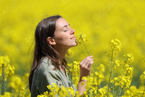 Woman smelling flowers in a yellow field