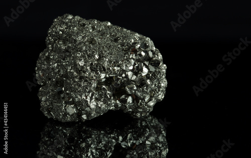 A cluster of pyrite crystals. Isolated on a black mirror background.