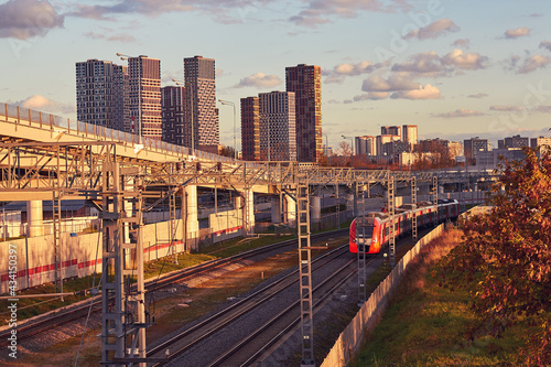 Electric train on the background of city buildings and a highway