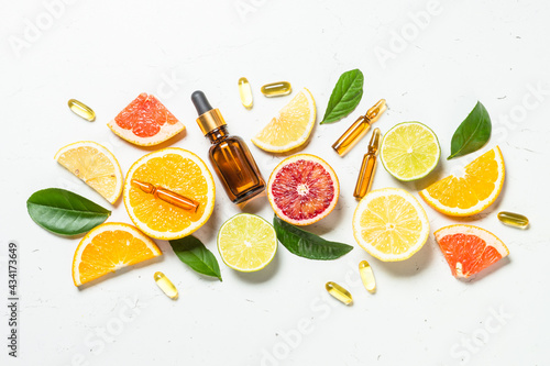 Vitamin C. Fresh citrus fruits with serum bottles, ampoules and pills. Top view with copy space.