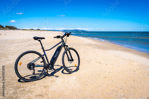 un vélo à assistance électrique sur une plage de sable blanc avec une mer bleue