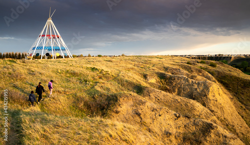 Medicine Hat Alberta Canada, May 13 2021: A family walks outdoors along a hiking trail in Seven Persons Coulee by the Sammis Tepee at sunset.