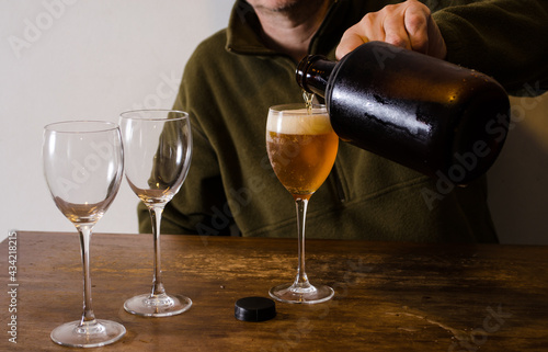 Man serving beer with a growler. Fresh homebrew beer on a glass.