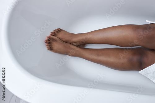 Top View On Black Female Legs Lying On Bathtub, Naked Soft Legs Skin, Close-up. Woman Is Going To Take Bath