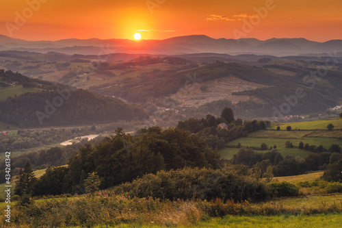 Picturesque sunset in Beskid Sądecki seen from the tower in Wola Krogulecka, with views of the mountains and fields. 