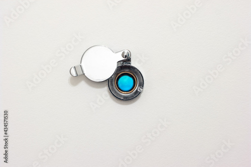Home door peephole with metal lid cover white wood background macro close up shot