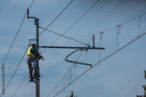 Painters or maintenance workers repairing catenary or electric poles for electricity on a railway or railroad line. Single worker on poles