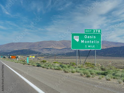 Roadside sign along Highway 80 with distance and directions to Oasis and Montello in Nevada.