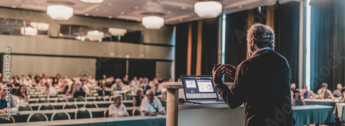 Senior public speaker giving talk at scientific conference.