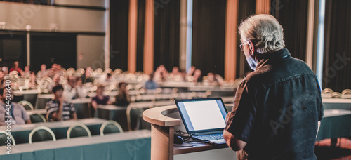 Senior public speaker giving talk at scientific conference.