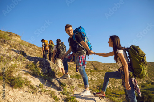 Group of tourists on hiking trip in mountains, copy space text. Team of active young people with backpacks mountaineering outdoors