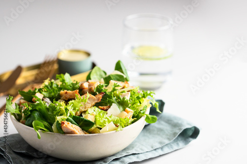 Healthy salad bowl with different lettuce, chicken, cheese and croutons on the table in reataurant.