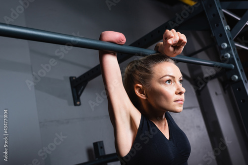 sportswoman with amputated forearm working out on horizontal bar