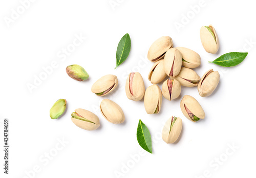 Flat lay of pistachio nuts with leaves on a white background.