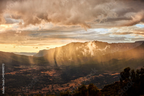 Aerial, dramatic view on illuminated rain over slopes of Bale mountains covered in Harenna forest, Ethiopia, Africa. Setting sun over Bale mountains national park. African nature.