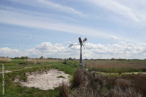 Small, metal windmill with a wind vane that pumps water. Called the Bosman mill in the nature area, polder, water storage area Saenegheest near the Dutch village of Bergen. Spring, May, Netherlands.