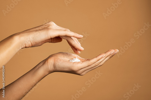 Woman hand applying lotion cream