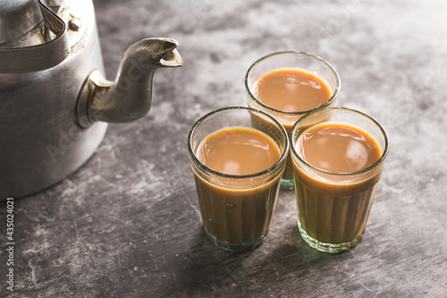 Indian chai in glass cups with metal kettle and other masalas to make the tea.