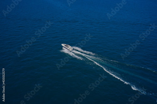 Top view of a white boat sailing in the blue sea. Aerial view luxury motor boat. A boat with a motor on blue water. Top view of the boat.