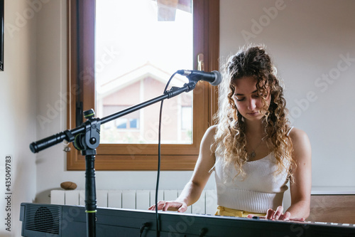 Young woman playing piano at home studio